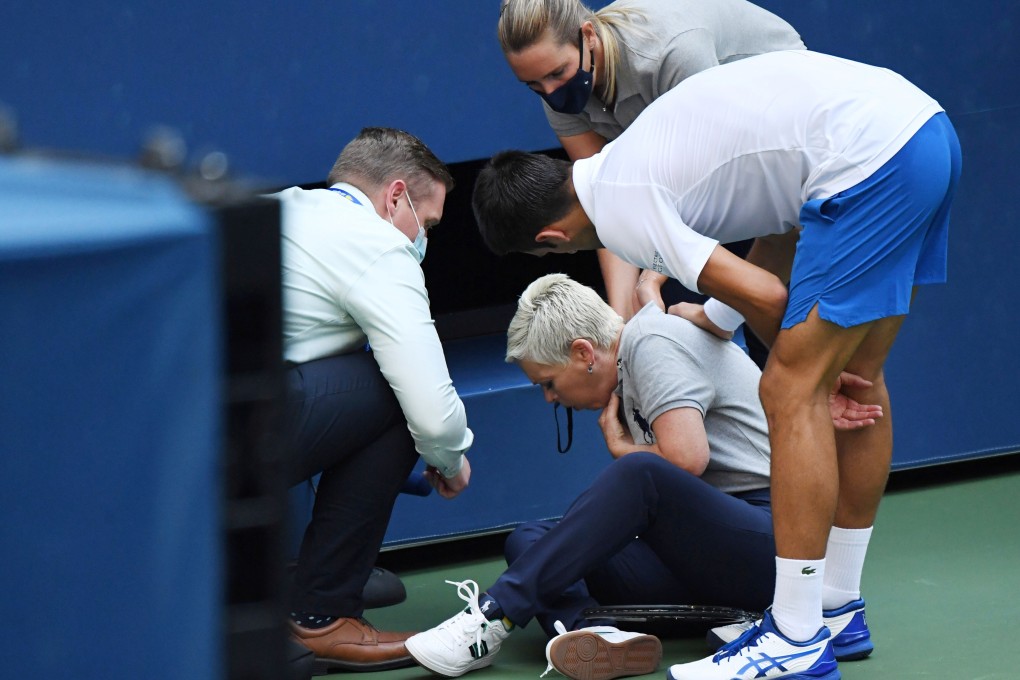 Novak Djokovic of Serbia and a tournament official tend to a linesperson who was struck with a ball by Djokovic on Sunday. Photo: Danielle Parhizkaran/USA Today