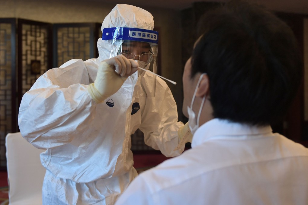 A worker in a protective suit takes a swab to test for Covid-19. Photo: AFP