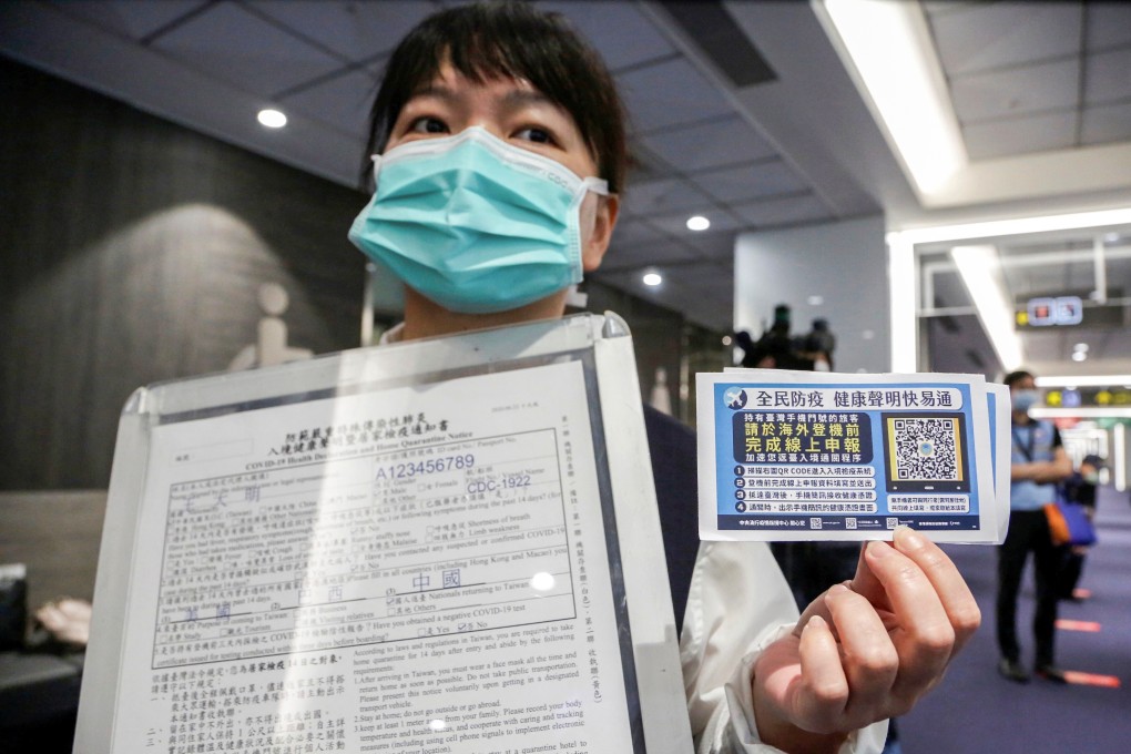 A member of airport staff holds up information boards regarding passenger health and home quarantine information declarations, at Songshan airport in Taipei on July 2. Photo: Reuters