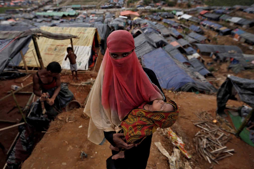 A Rohingya refugee carries her child in a refugee camp in Cox’s Bazar, Bangladesh. Photo: Reuters