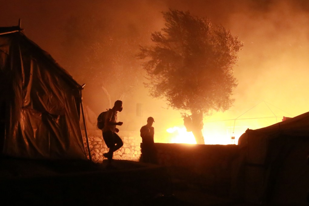 Migrants are seen leaving as a fire burns in the Moria camp on the island of Lesbos, Greece. Photo: AFP