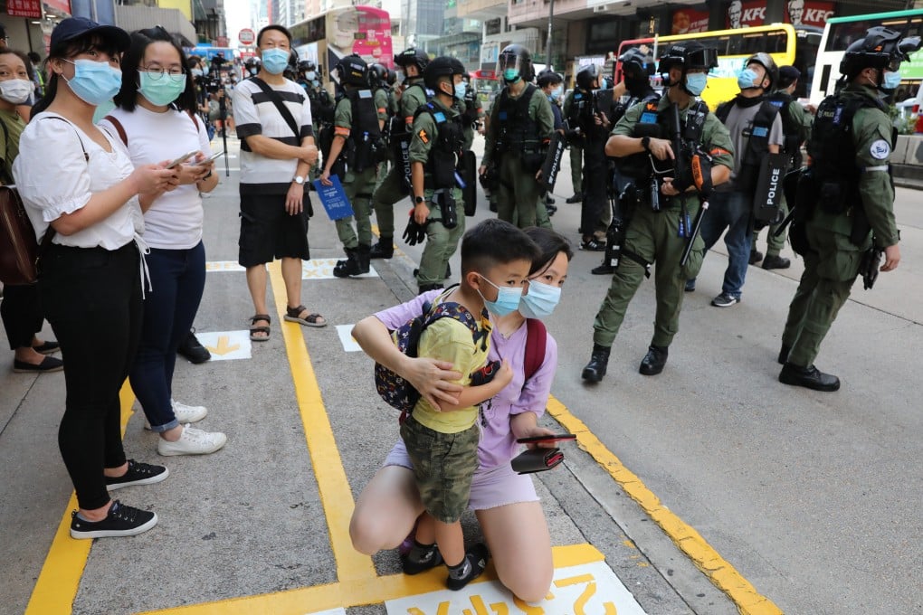 A woman holds a child in Mong Kok as police officers stand ready to prevent anti-government protesters gathering to rally on September 6. Photo: May Tse