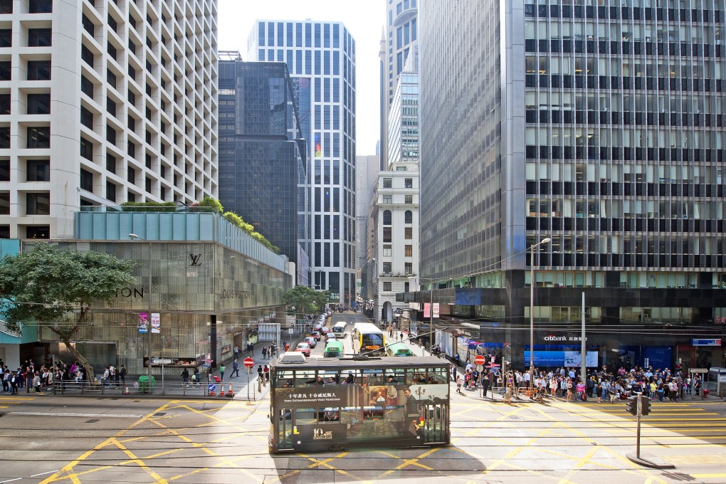 An iconic heritage double-decker tram passes a street junction in Central as it rides down the tramlines in the dedicated central reservation between high-rise skyscrapers in this street scene cityscape of the shopping and business district, Hong Kong Island. Photo: Getty Images