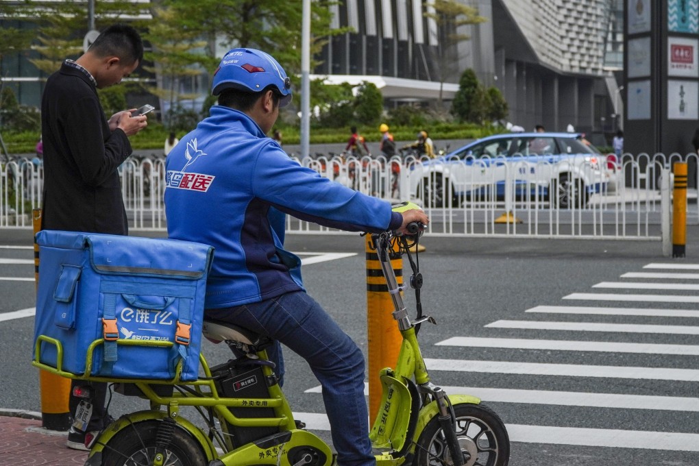 A Ele.me delivery driver waits to cross the pedestrian crossing in the Futian district in Shenzhen, 2019. Photo: SCMP/Roy Issa