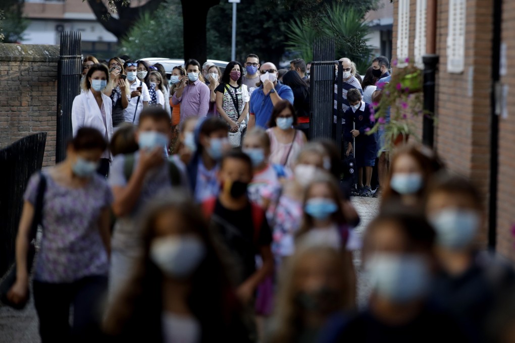 Relatives and parents look at pupils entering the San Policarpo parish as Italian schools reopen in Rome on Monday. Photo: AP