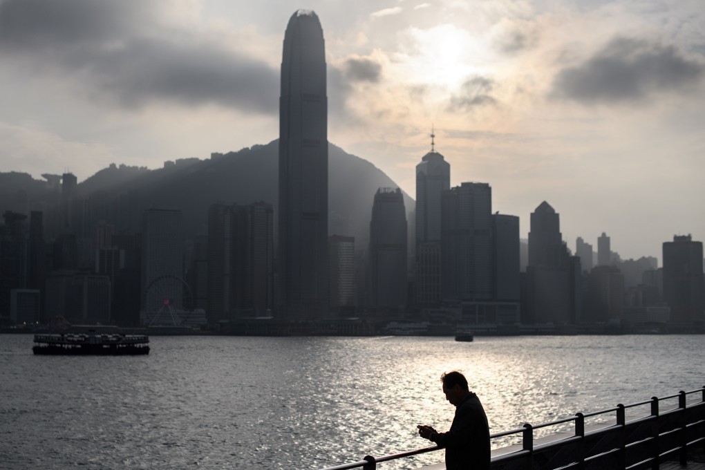 This file photo taken on January 21, 2020 shows a man using his phone as he stands on a viewing point popular with tourists that faces the skyline (back) of Hong Kong island. Photo: AFP