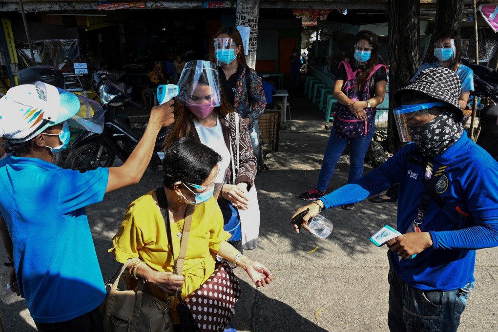 Philippine passengers wearing face shields have their temperature taken before boarding a bus in Manila. Photo: AFP