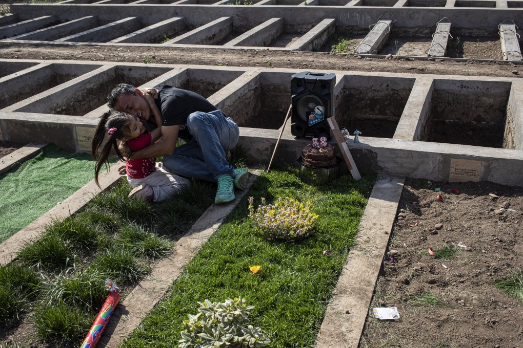 A girl embraces her father as they visit his wife’s grave, who died of the coronavirus in Santiago, Chile. Photo: AP