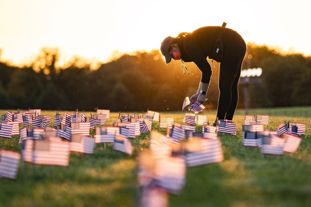A supporter of the Covid Memorial Project places American flags for the dead on the National Mall in Washington. The US death toll has passed 200,000. Photo: EPA