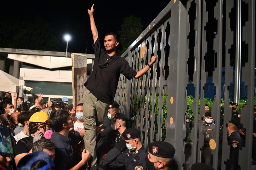 Pro-democracy activist Panupong “Mike” Jadnok makes a three-finger salute to anti-government protesters after placing a sticker outside the closed main gate of Thailand's parliament as lawmakers held a debate inside. Photo: AFP