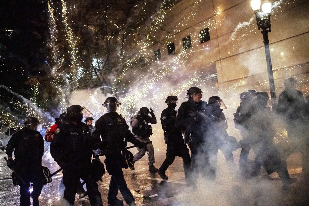 A firecracker explodes behind police during a protest in Portland following the results of a grand jury investigation into the police shooting death of Breonna Taylor. Photo: AFP