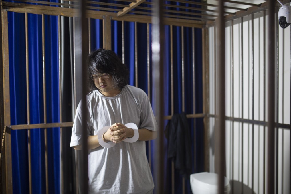 A university student, Feng Hanchen, wears a pair of paper handcuffs during the 24 hours he spent in a cage in Tang Jie's living room in Fuyang, China, as part of an art project to highlight social injustice. Photo: The Starving Artist Project