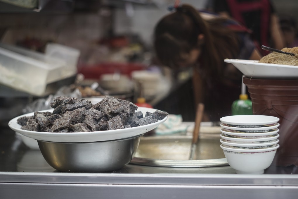 Pig’s blood cakes piled on a large plate displayed on a cooking counter in a food booth in a traditional market in Tainan City, Taiwan.