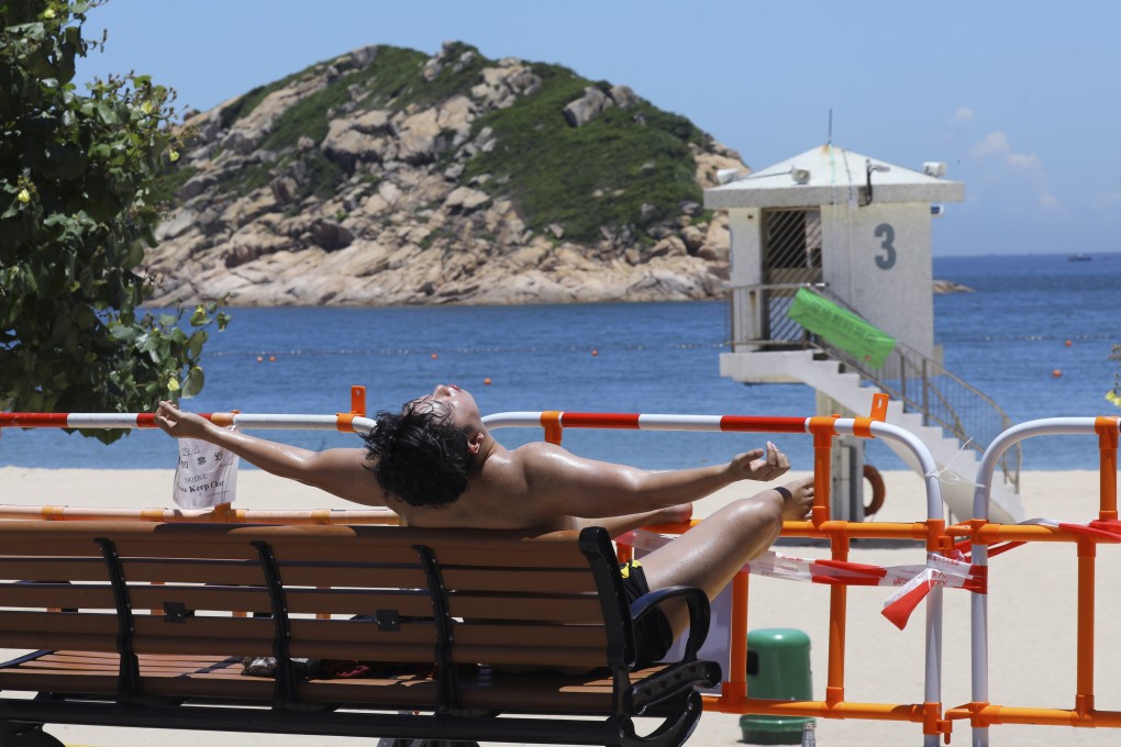 A man sunbathes behind the barricades at Shek O beach on July 26, days after Hong Kong’s beaches were closed. Photo: SCMP / Dickson Lee