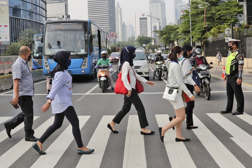 Jakarta residents wearing face masks as a precaution against Covid-19 cross the road in the capital’s central business district. Photo: AP