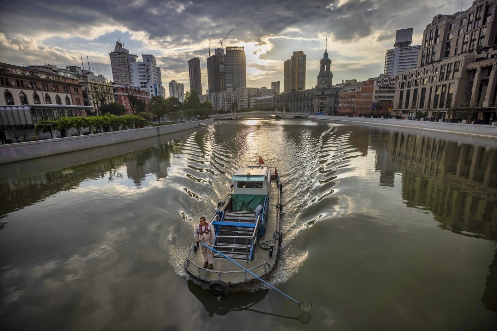 A man on the boat cleans a canal in Shanghai, China on Thursday. Photo: EPA-EFE