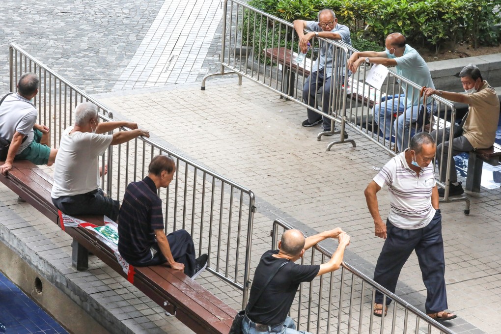 A group of elderly men sit across from each other behind metal barricades. Hong Kong is still trying to snuff out a third wave of Covid-19, with daily cases on a general decline. Photo: K. Y. Cheng
