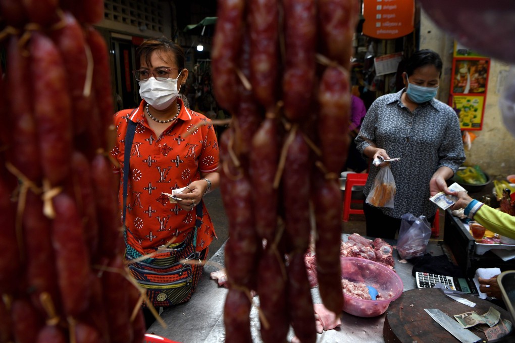 Women wearing masks buy pork at a market in Phnom Penh on September 15. The draft legislation includes a provision banning face masks. Photo: AFP