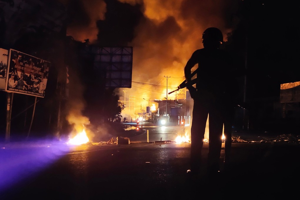 An armed Indonesian policeman stands guard near a burning building after hundreds of demonstrators marched near Papua's biggest city, Jayapura, on August 29 last year. Photo: AFP