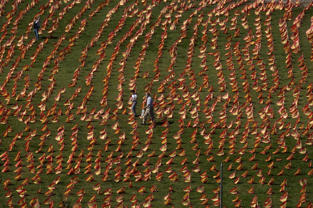 People walk among the Spanish flags placed in memory of coronavirus victims in Madrid, Spain, one of the early epicentres of the pandemic. Photo: AFP