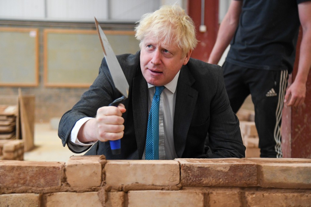 British Prime Minister Boris Johnson builds a brick wall during a visit to Exeter College on Tuesday. Photo: PA Wire/dpa