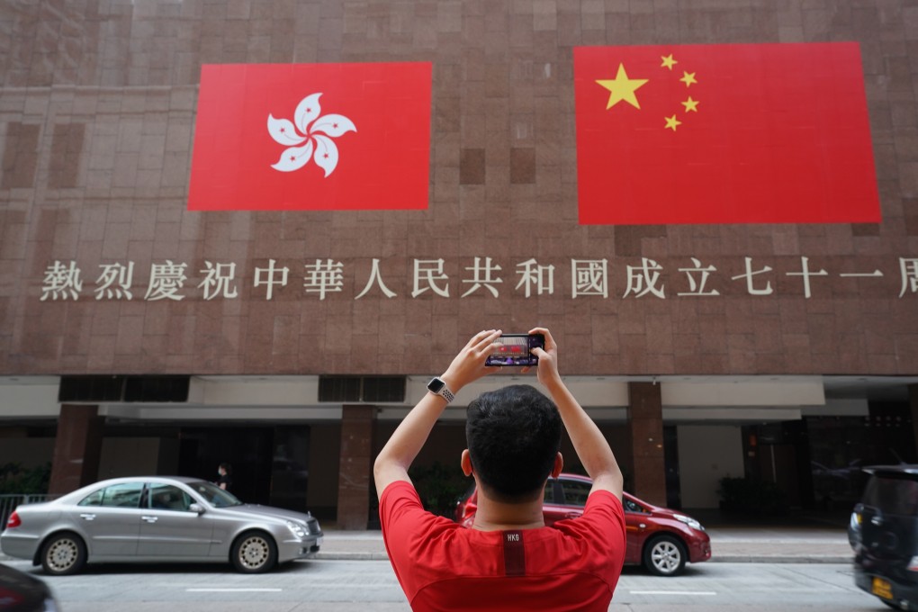 A man takes a picture of the flags of the People’s Republic of China and Hong Kong. Photo: Felix Wong