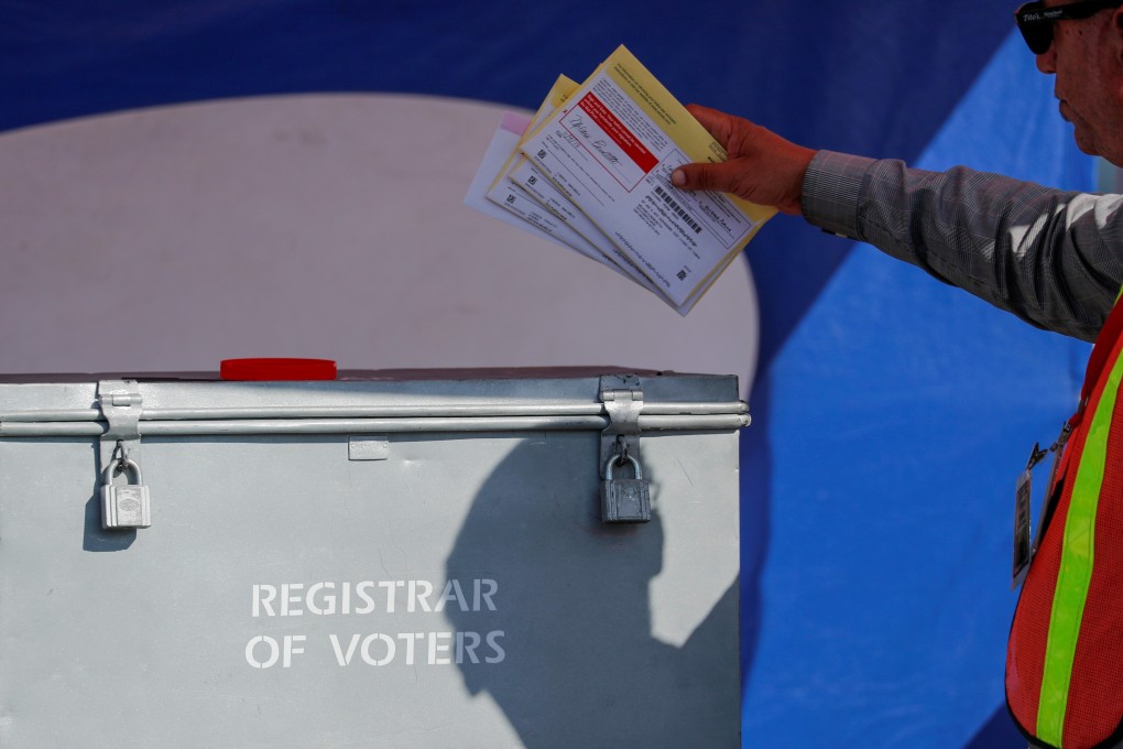 An election worker places mail-in ballots into a ballot box in San Diego, California, in 2018. File photo: AFP