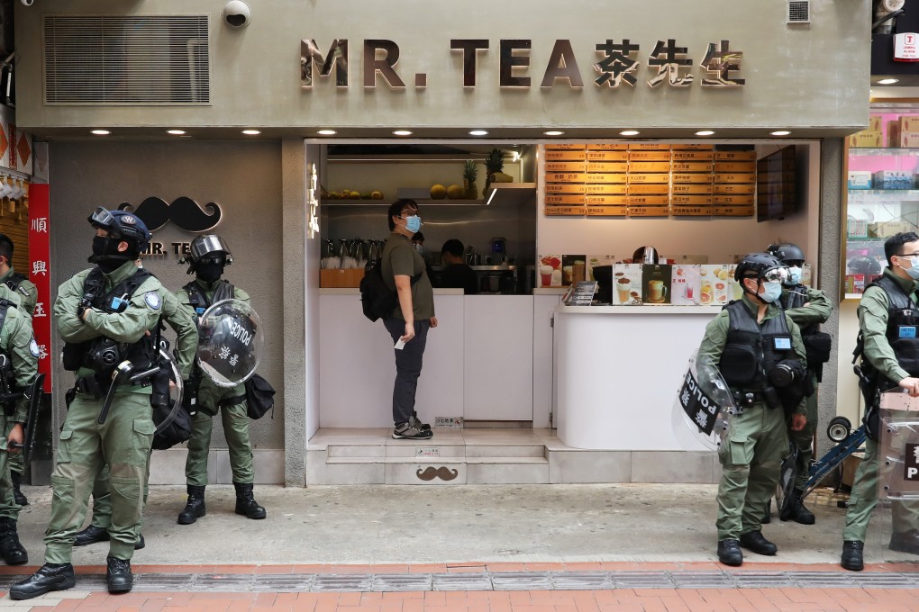 A man orders a drink at a tea shop as police officers stand outside in Causeway Bay on Thursday. Photo: Nora Tam
