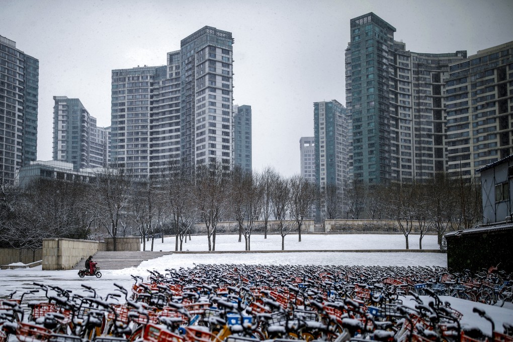 A person wearing a face mask rides an electric scooter with shared bikes parked nearby in Beijing on February 5. Picture: Reuters