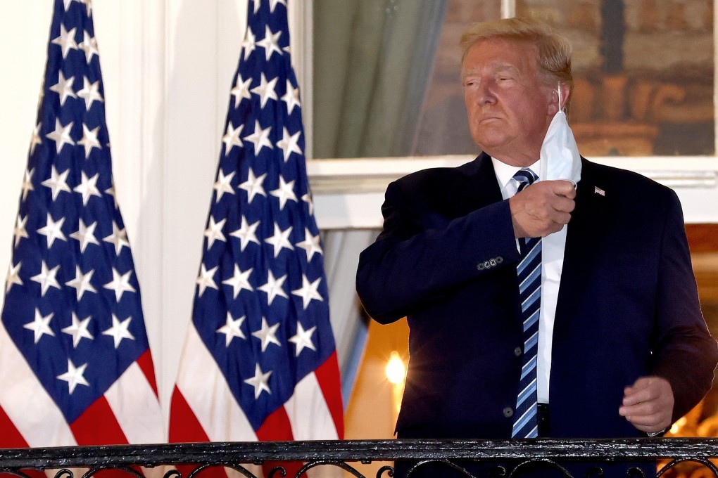 US President Donald Trump removes his mask upon returning to the White House from Walter Reed National Military Medical Center on Monday. Photo: TNS