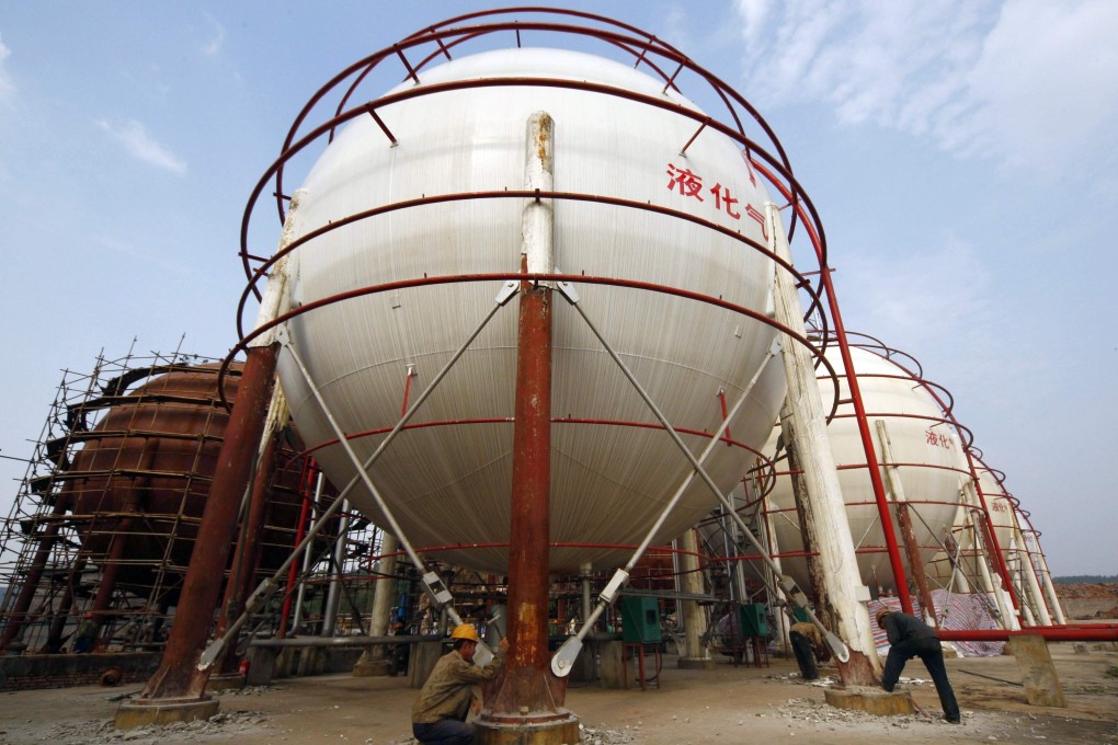Labourers working under storage tanks at a refinery in Suining, Sichuan province, on October 22, 2009. Photo: Reuters