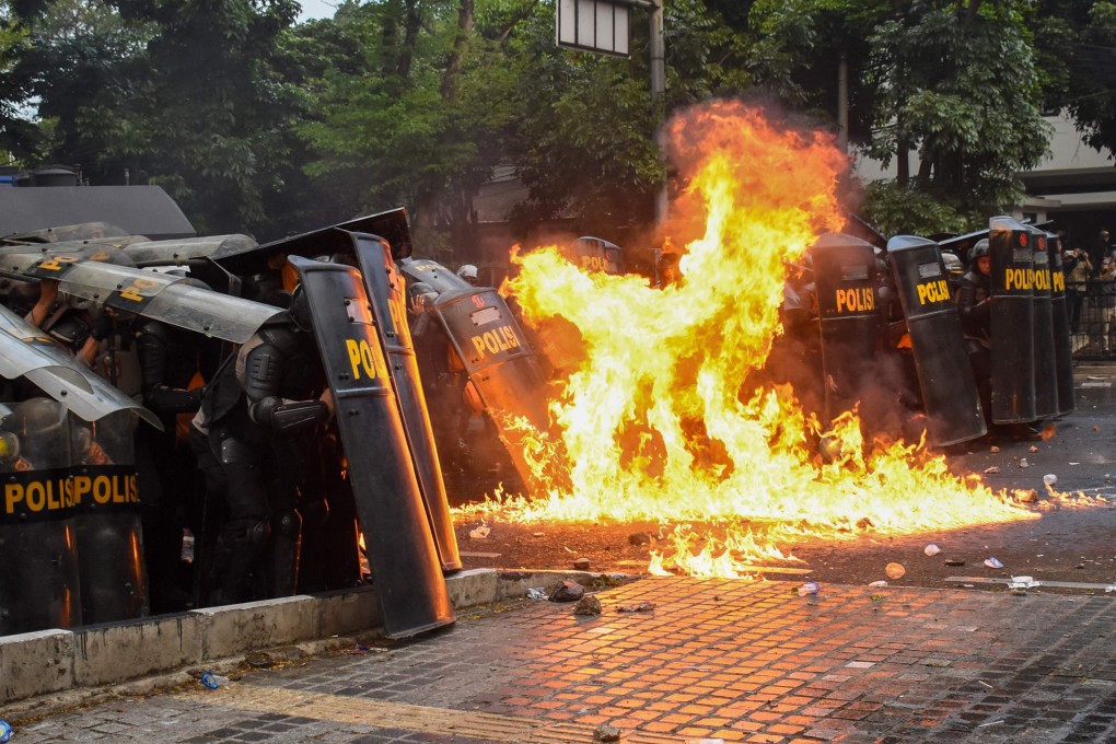 Riot police officers are hit by a petrol bomb in Bandung on Wednesday. Photo: AFP