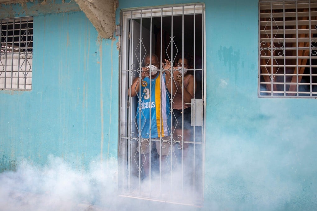 Santo Domingo residents watch from their homes as disinfectant is sprayed in the street as a preventive measure against the coronavirus in April. Photo: AFP