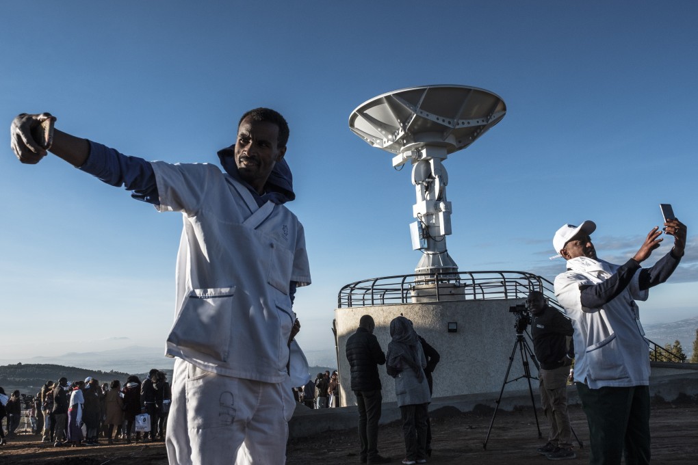 People take selfies in front of a satellite antenna in Ethiopia. Photo: AFP