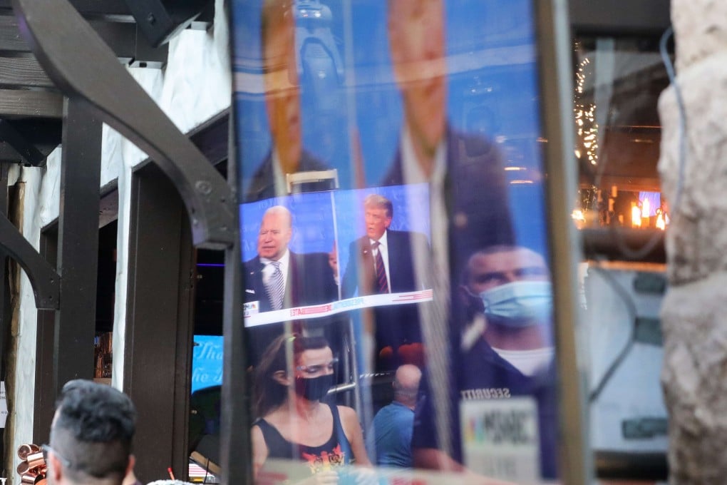 People wearing face coverings are reflected in a TV screen as people sit to watch a broadcast of the first debate between President Donald Trump and Democratic presidential nominee Joe Biden at The Abbey, with socially distanced outdoor seating, on September 29, 2020 in West Hollywood, California. Photo AFP