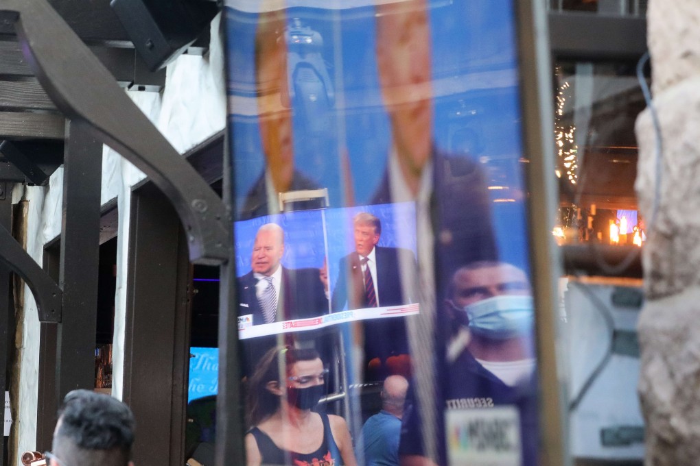 People wearing face coverings are reflected in a television screen during the first debate between President Donald Trump and Democratic presidential nominee Joe Biden. Photo: AFP