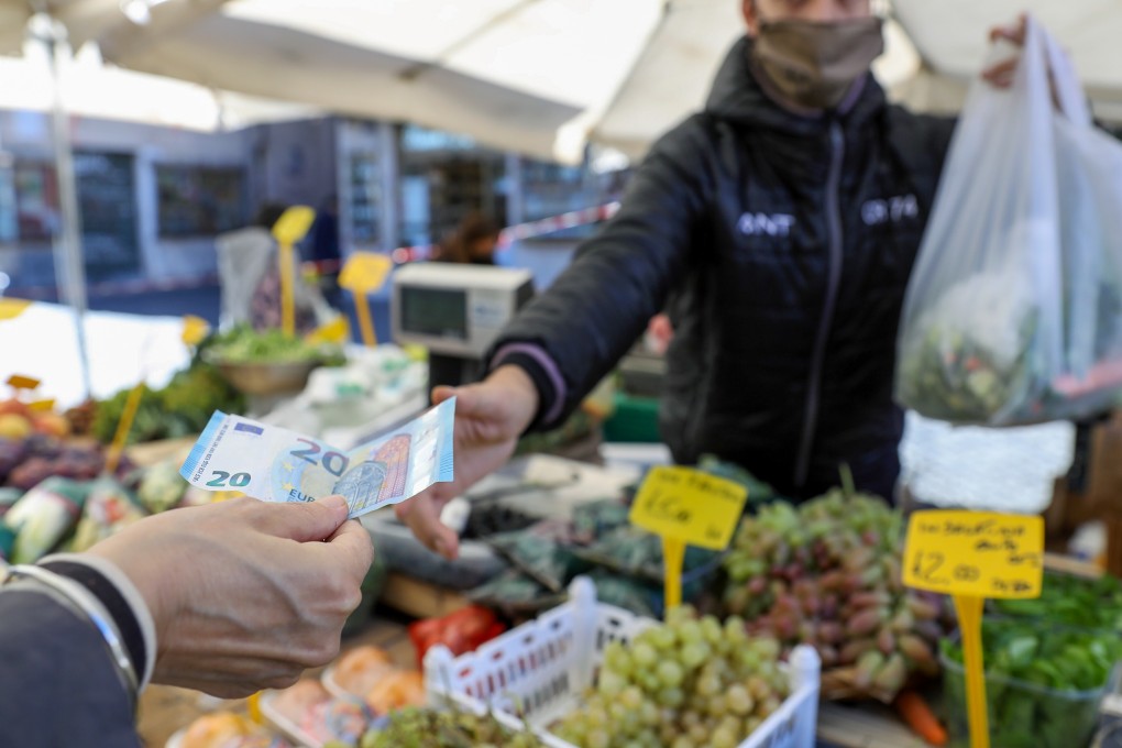 A customer hands a 20 Euro banknote to a vendor at a stall selling fruit and vegetables in Rome, Italy, earlier this month. Photo: Bloomberg