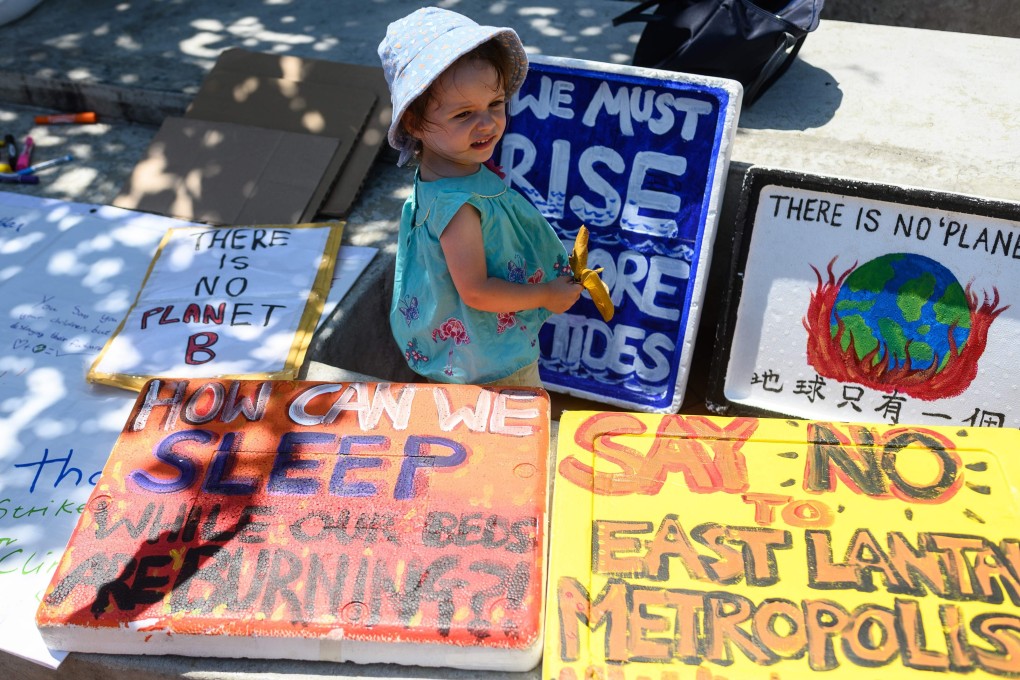 A child stands next to placards before a climate strike rally in Central on September 20, 2019. Despite several firms making high-profile pledges to improve their sustainability and business practices, the effectiveness of relying on companies’ enlightened self-interest remains unclear. Photo: AFP