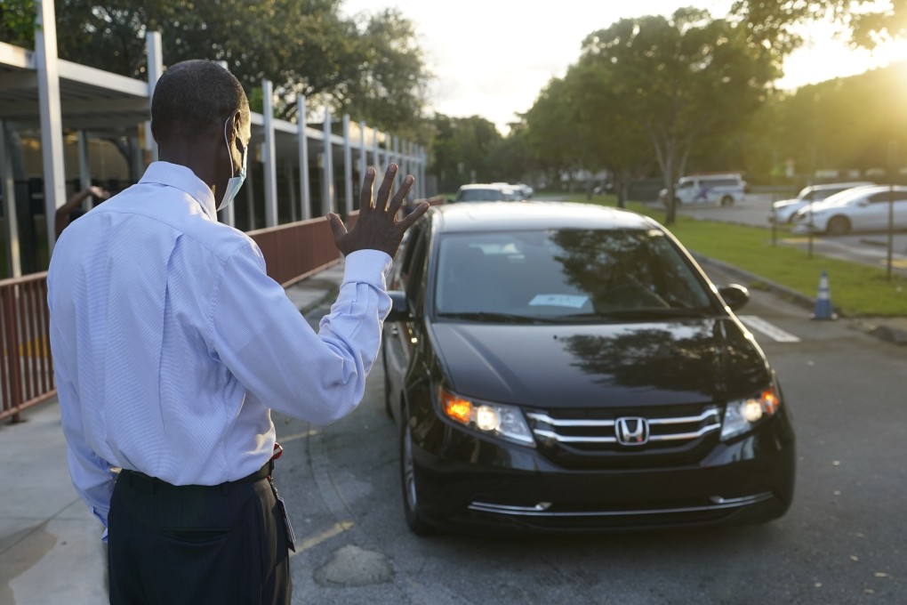 A US school employee waves to parents as they drop off their children at school. Photo: AP Photo
