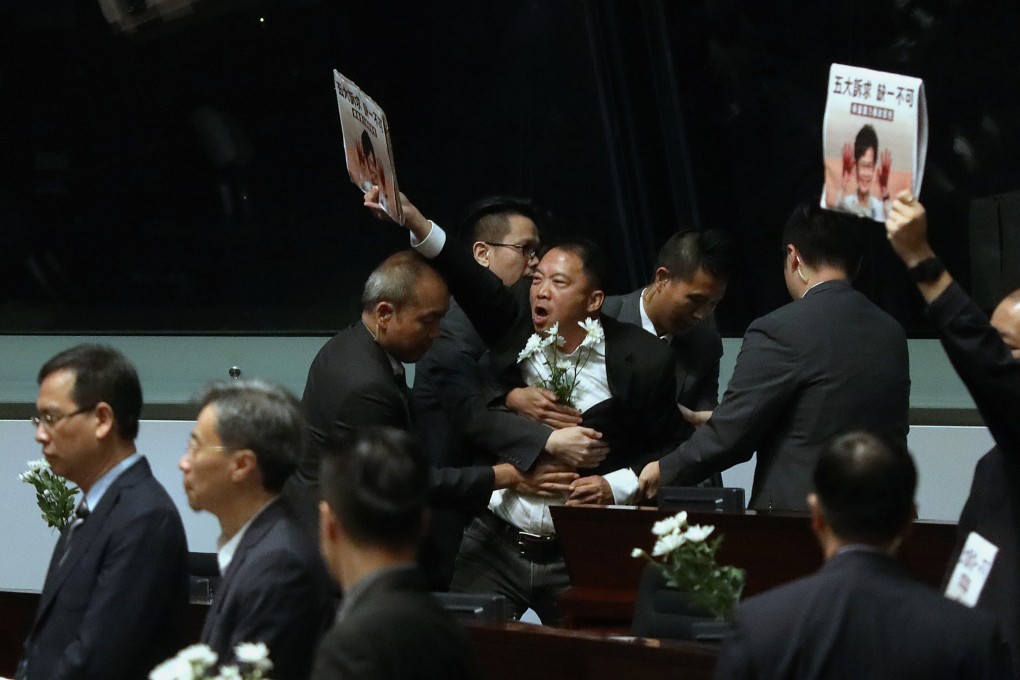 Legco security guards hold back opposition lawmaker Wu Chi-wai as he protests during the chief executive’s question-and-answer session after the 2019 policy address. Photo: Dickson Lee