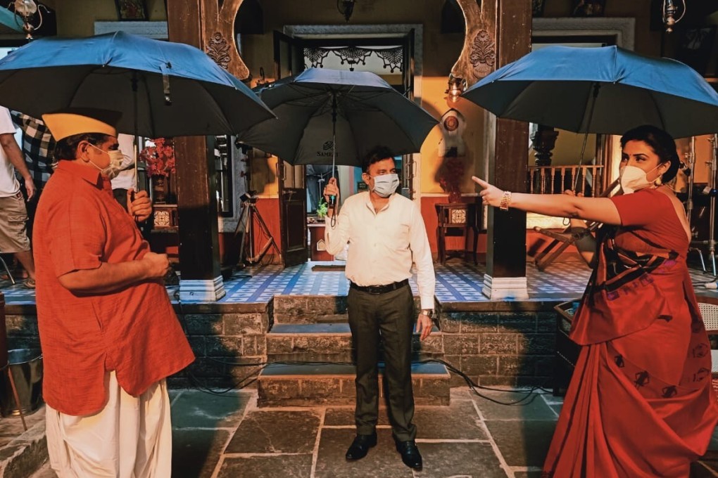 Actors rehearse a scene for Indian television series Bhakharwadi – holding umbrellas to make sure they are standing far enough apart for social distancing. Photo: DPA
