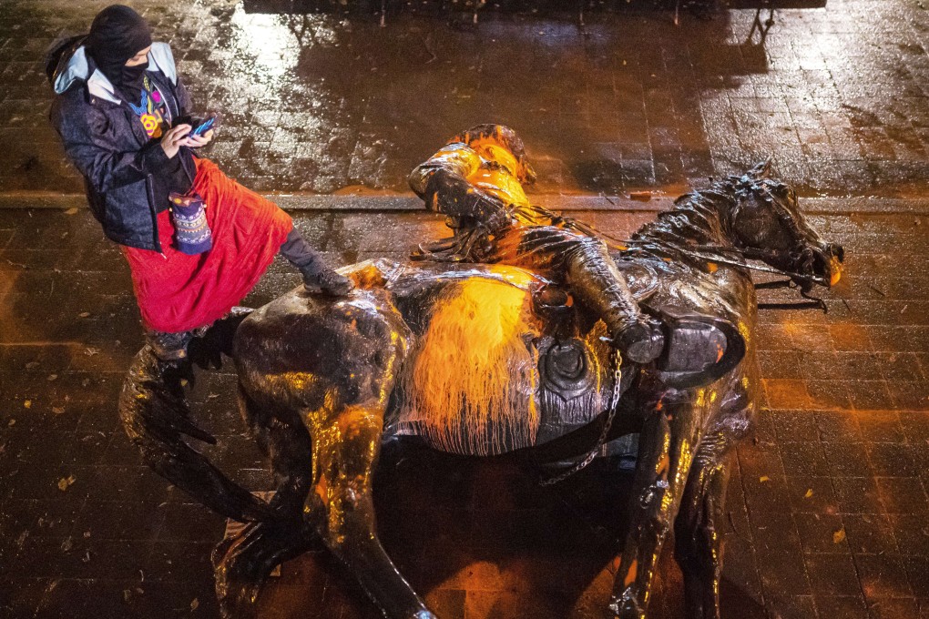 A protester stands over a toppled statue of President Theodore Roosevelt in Portland, Oregon. Photo: AFP