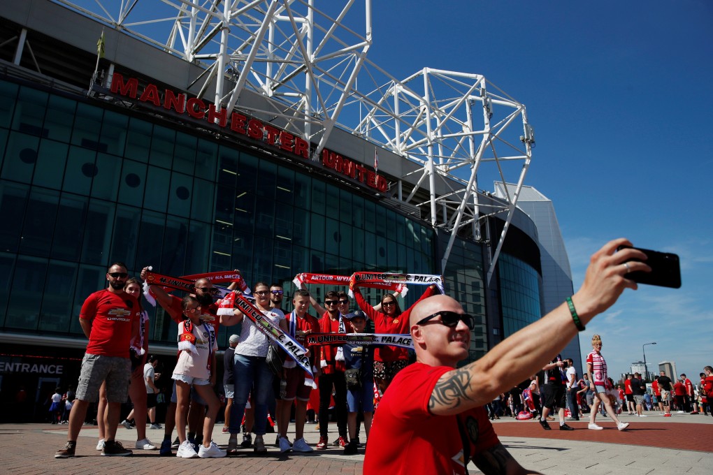 Manchester United fans pose for a photo outside the club’s Old Trafford stadium. Photo: Reuters