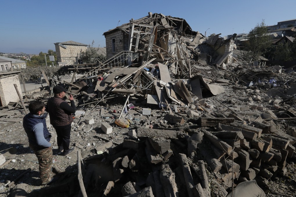 Men look at the ruins of a house following shelling in the breakaway region of Nagorno-Karabakh. Photo: Reuters