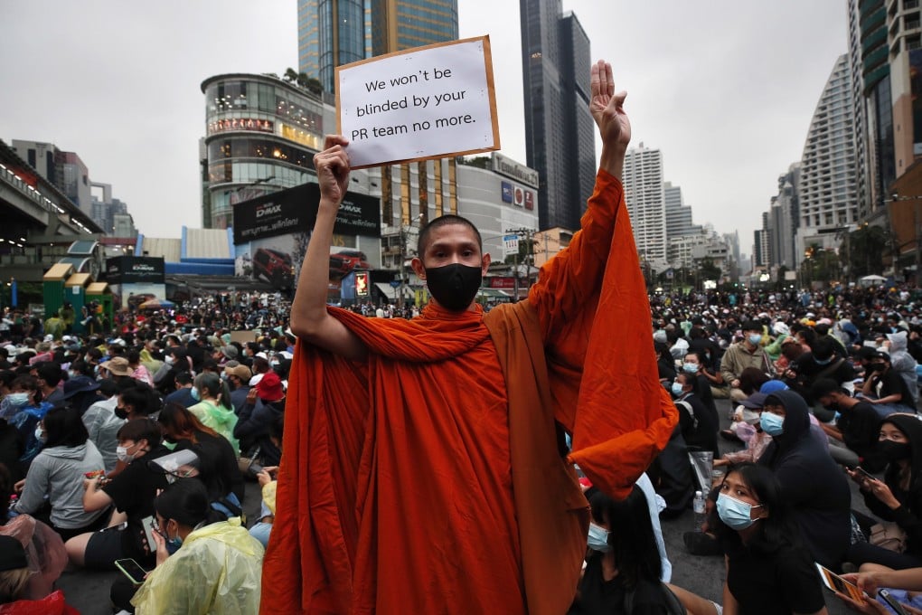 A Buddhist monk shows the three-finger salute while holding a placard among pro-democracy demonstrators during an anti-government protest in Bangkok. Photo: EPA