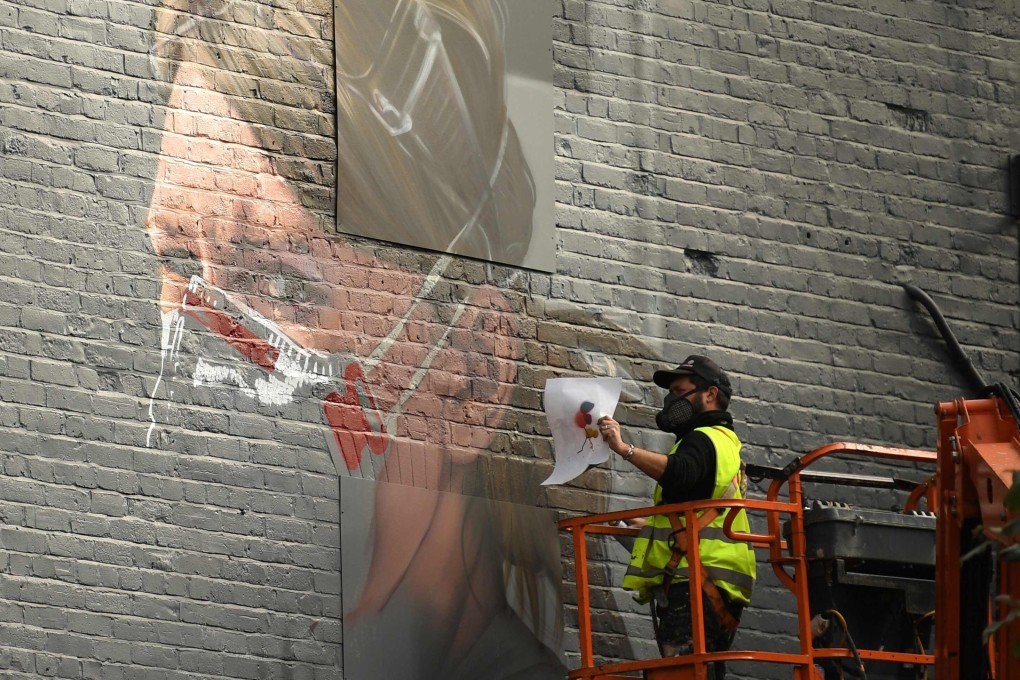 An artist creates a mural of a NHS worker in north Manchester, England. Photo: AFP