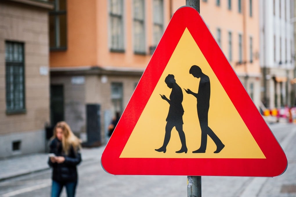 A road sign warning against pedestrians focusing on their smartphones is seen near the old town in Stockholm. Sweden is the latest European country to ban use of telecoms gear from Huawei Technologies and ZTE Corp for upcoming 5G mobile networks. Photo: Agence France-Presse