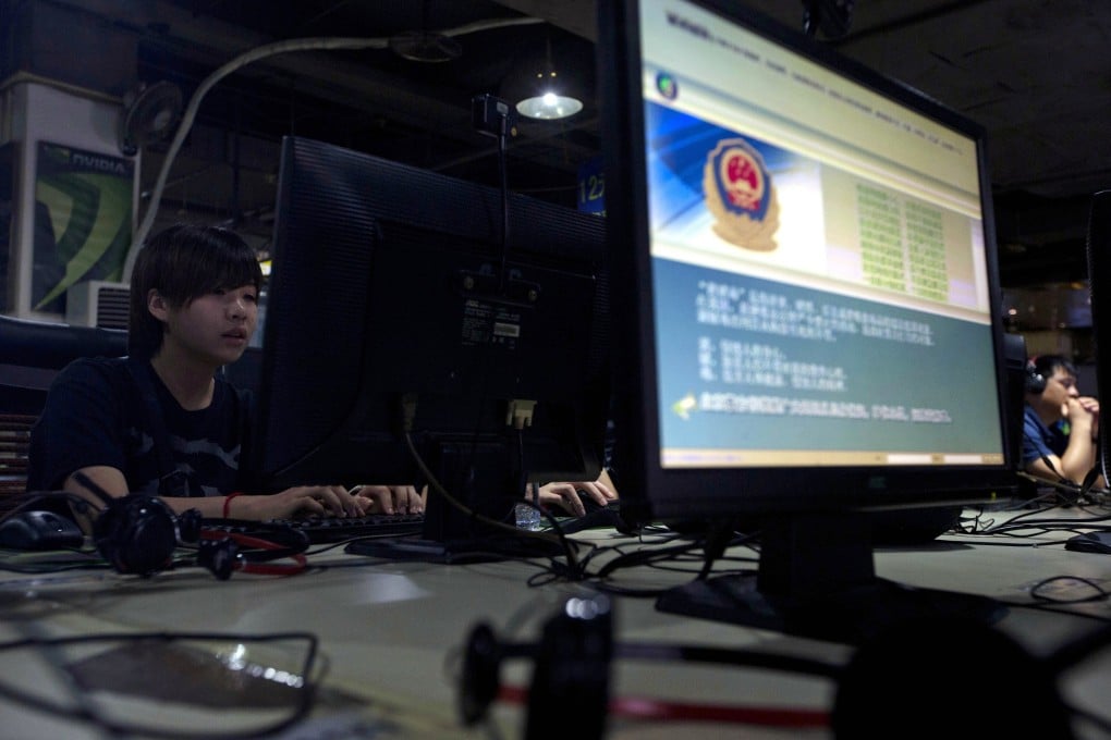 Computer users sit near a monitor display with a message from the Chinese police on the proper use of the internet at an internet cafe in Beijing. Photo: AP