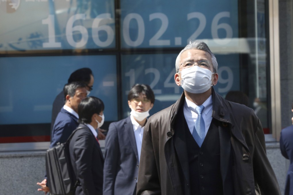 People walk by an electronic stock board of a securities firm in Tokyo, Japan in March 2020. Stocks in Asia-Pacific markets get a boost from progress in US stimulus talks. Photo: AP