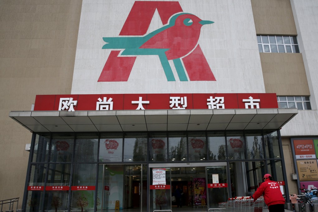 An employee carries shopping trolleys into Sun Art Retail Group's Auchan hypermarket store in Beijing. Photo: Reuters
